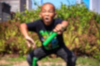 a young boy squats down in front of a building