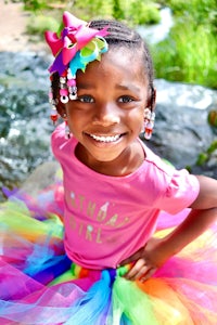 a young girl in a colorful tutu smiles for the camera